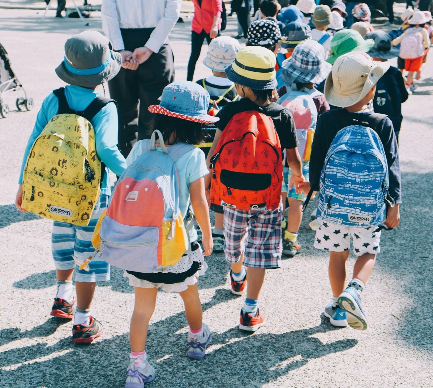 Children with colorful backpacks walk into school together