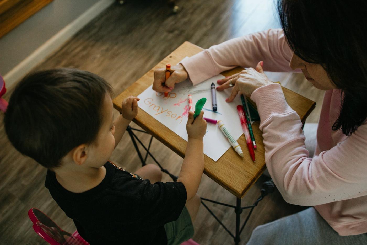 A guide and child color together at a table