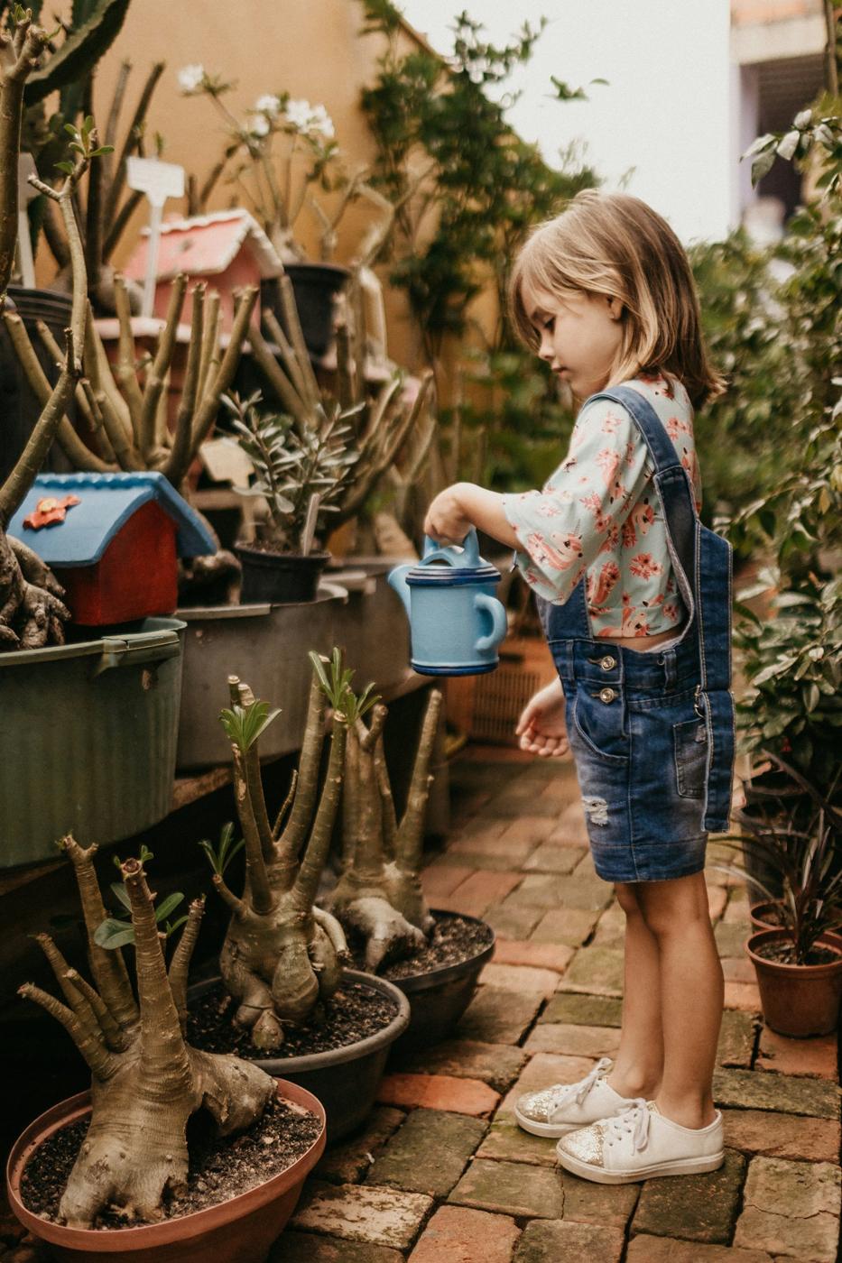 A girl waters potted plants in the school garden