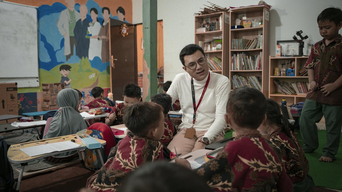 The head of school sits with a circle of children in the library